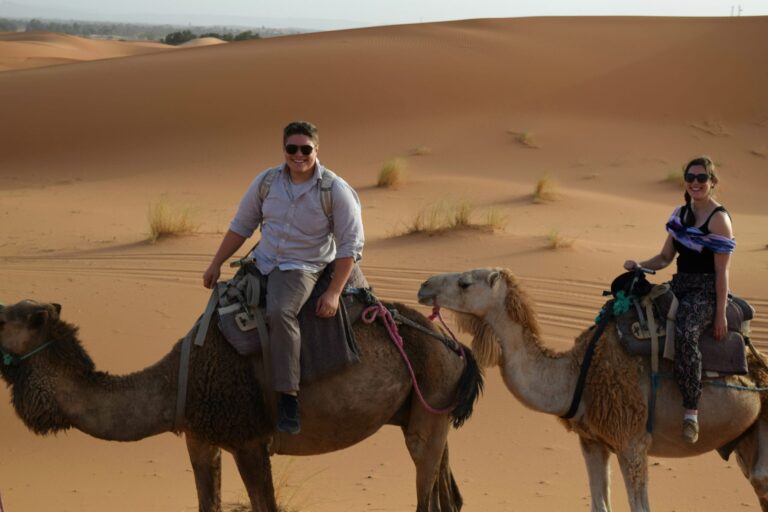 kate storm and jeremy storm riding camels near erg chebbi on a morocco sahara desert tour